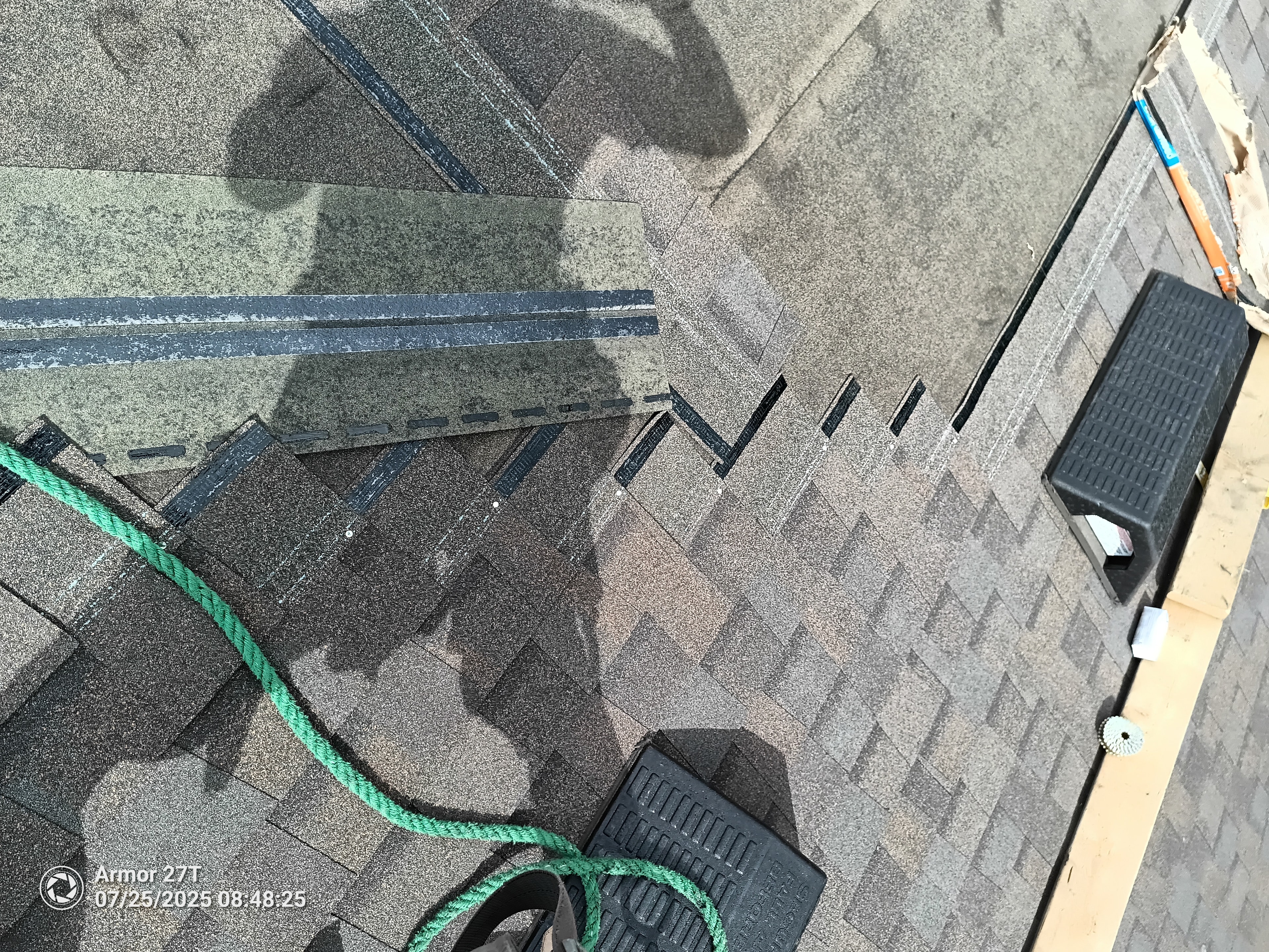 Shingle installation in progress with safety rope on residential roof