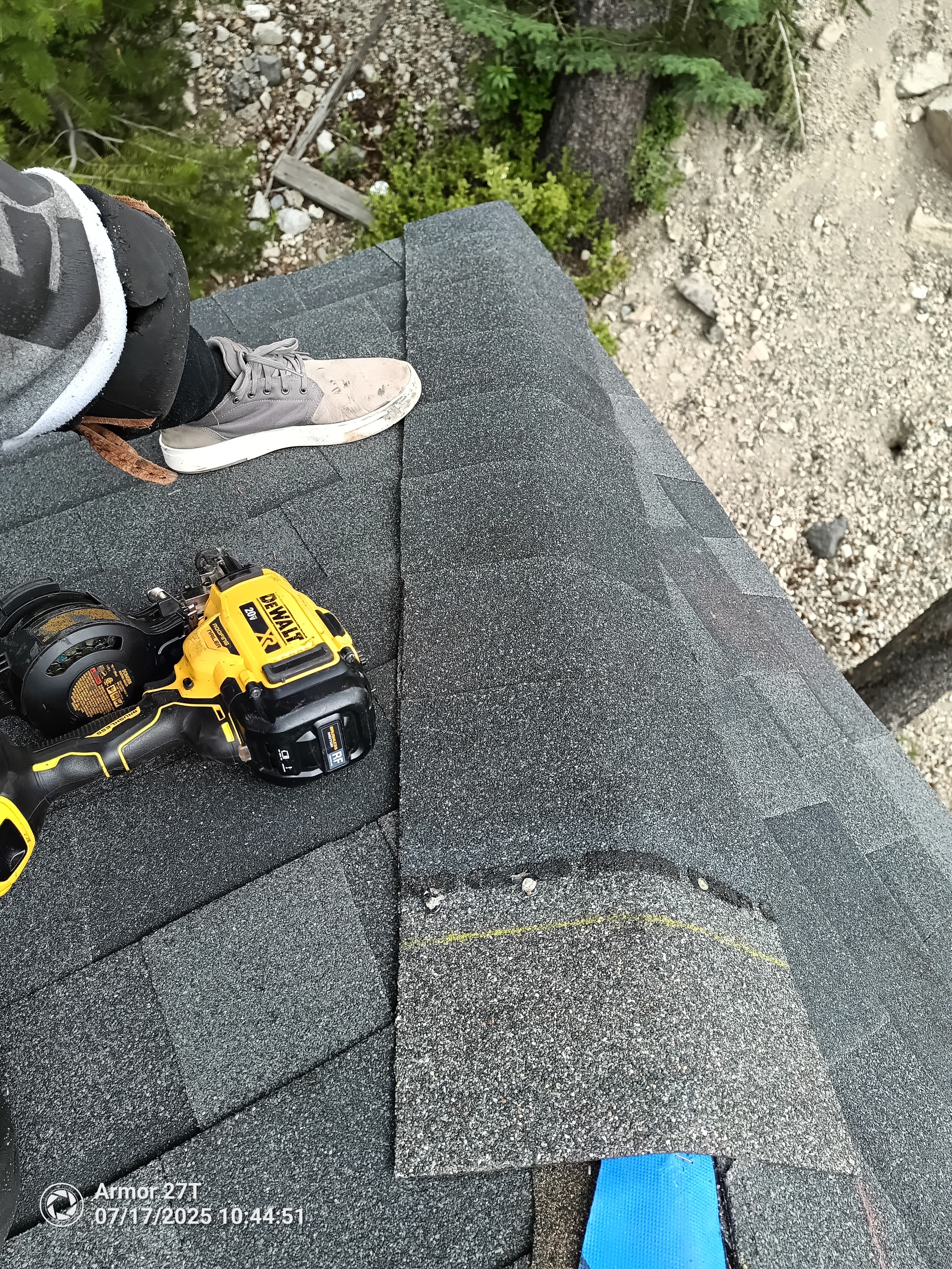 Roofer installing ridge cap shingles with DeWalt nail gun