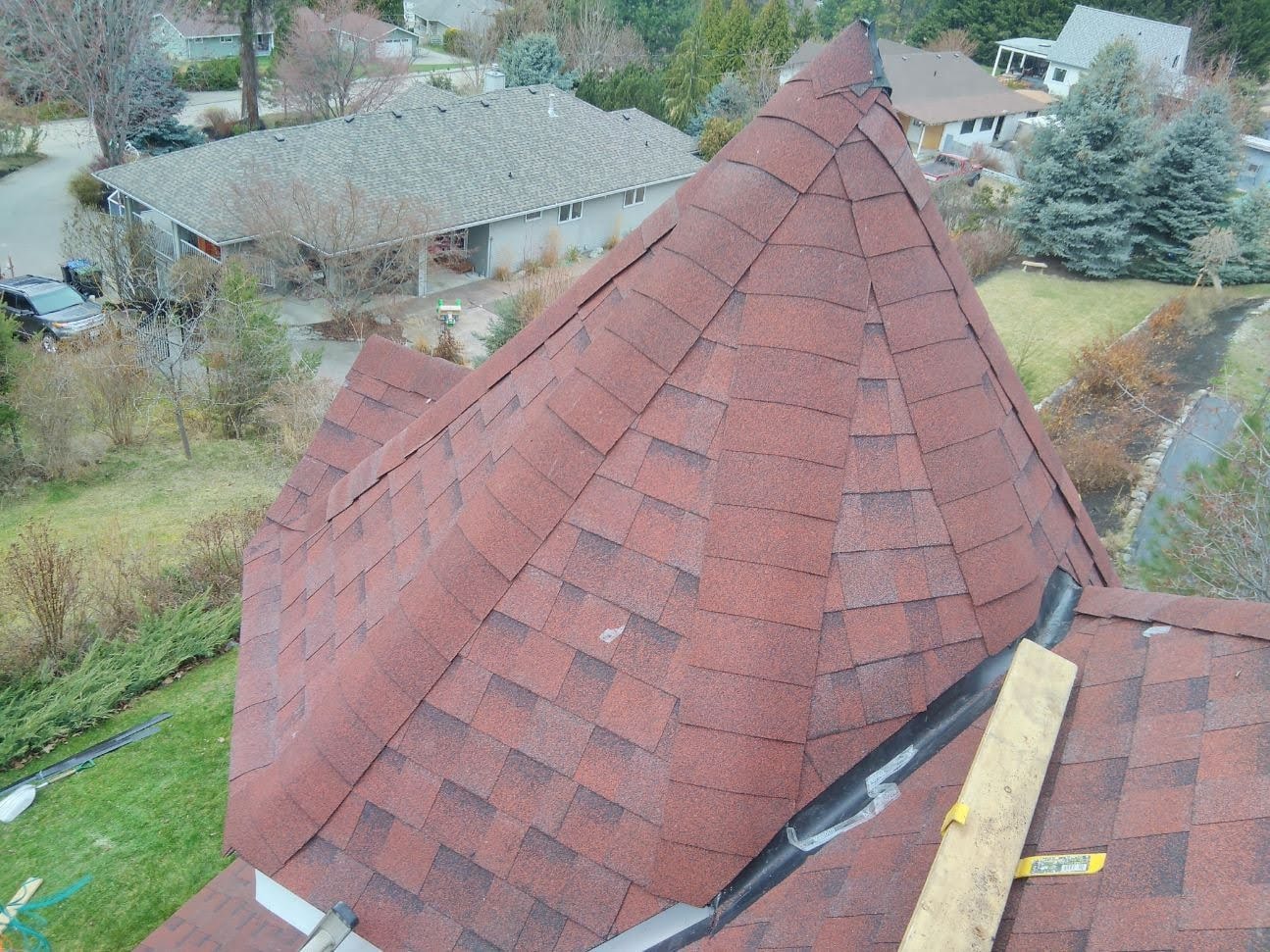 Aerial view of completed red/burgundy shingle roof on residential home in Kelowna