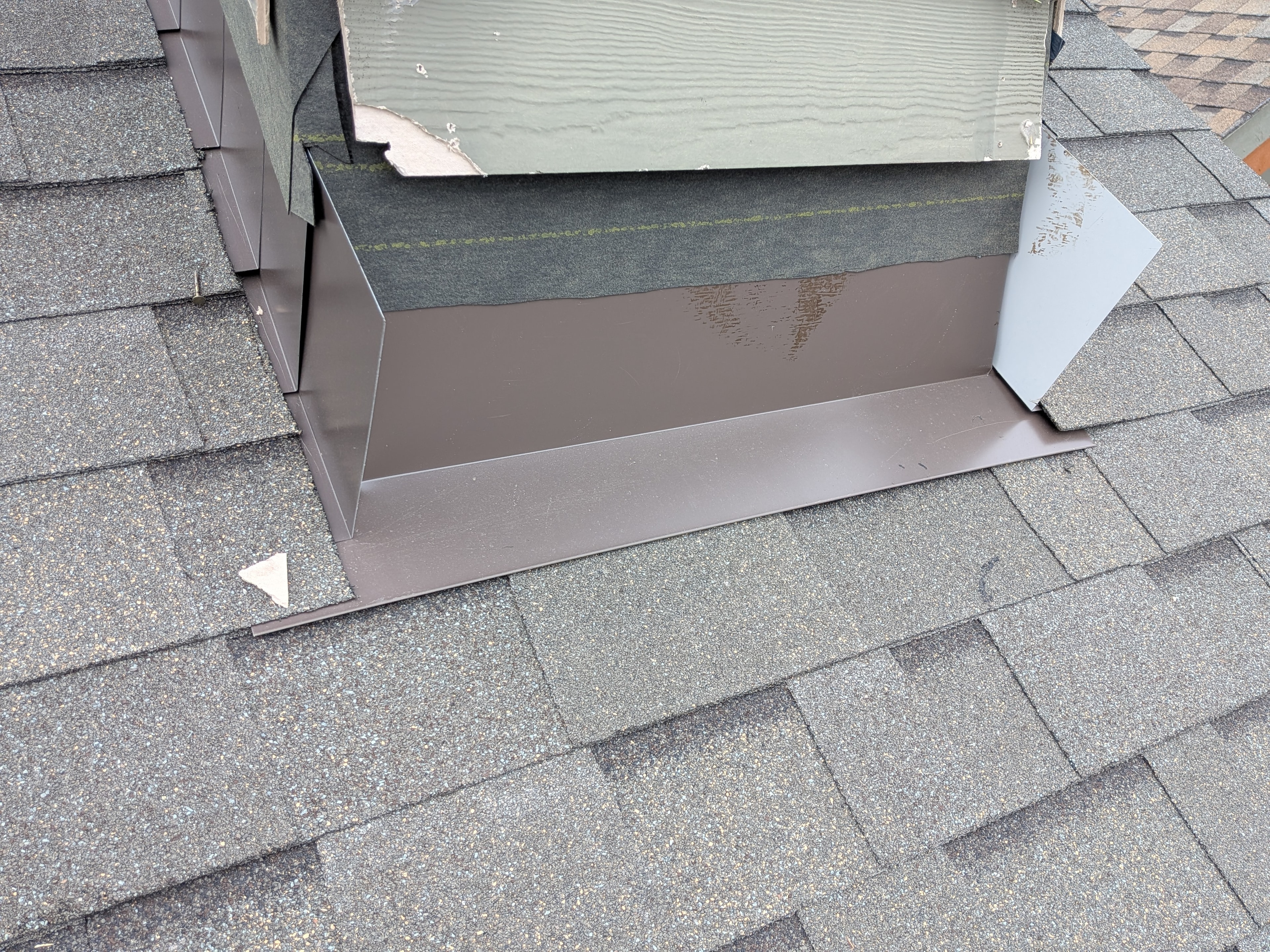 Skylight flashing detail with brown metal counter-flashing on grey shingle roof