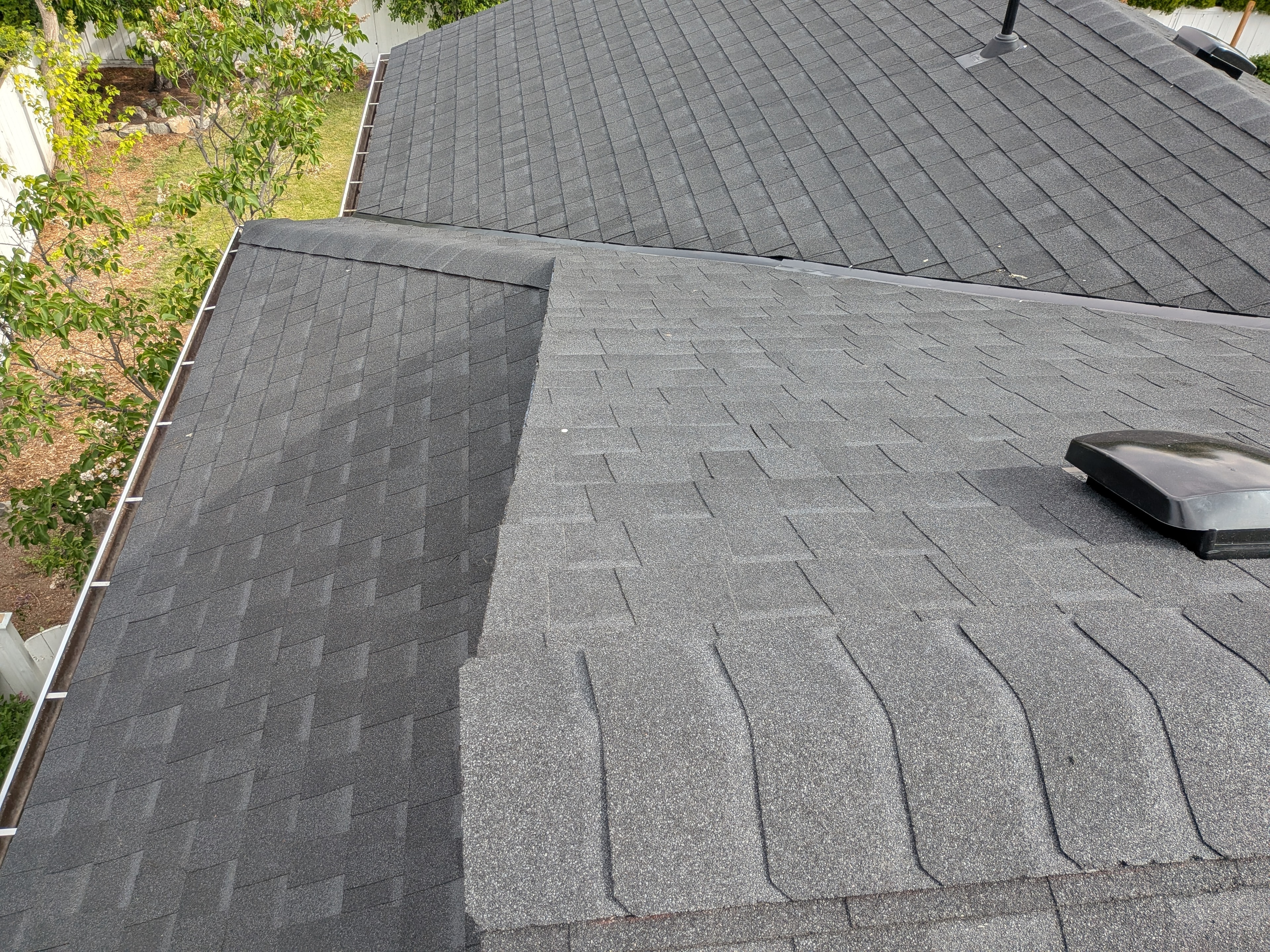 Completed dark grey shingle reroof with gutters and roof vents on residential home