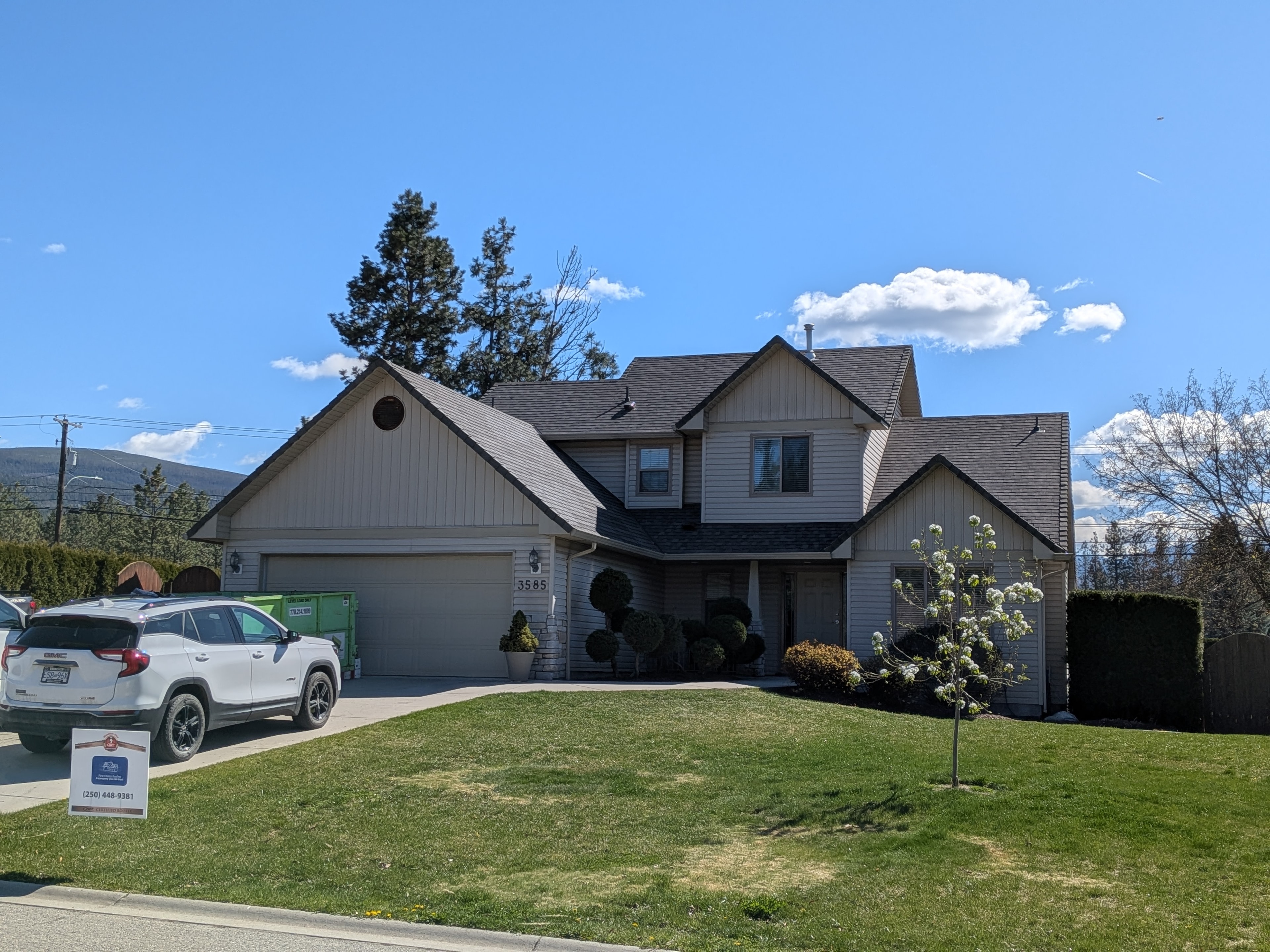 Completed brown shingle reroof on large craftsman home with First Choice Roofing yard sign