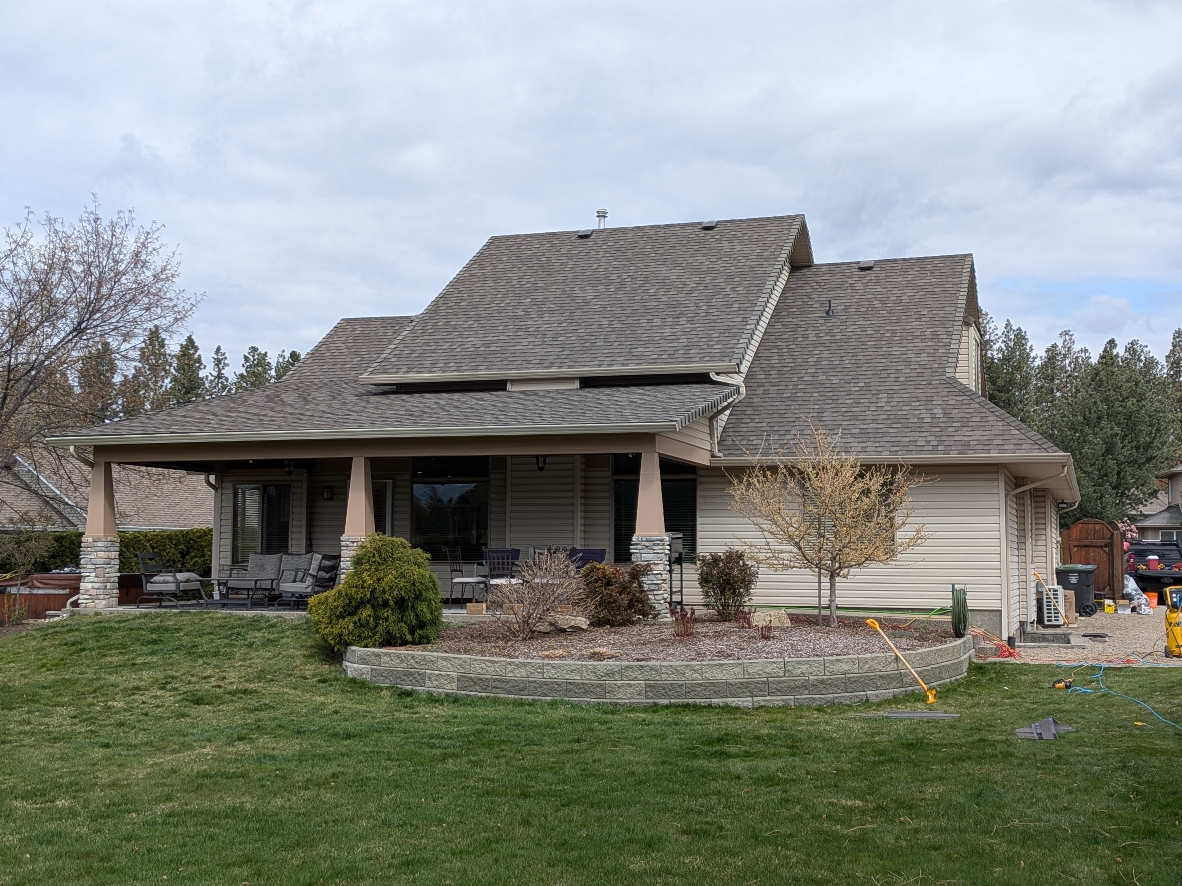 Completed grey shingle reroof on large home with covered patio and stone columns