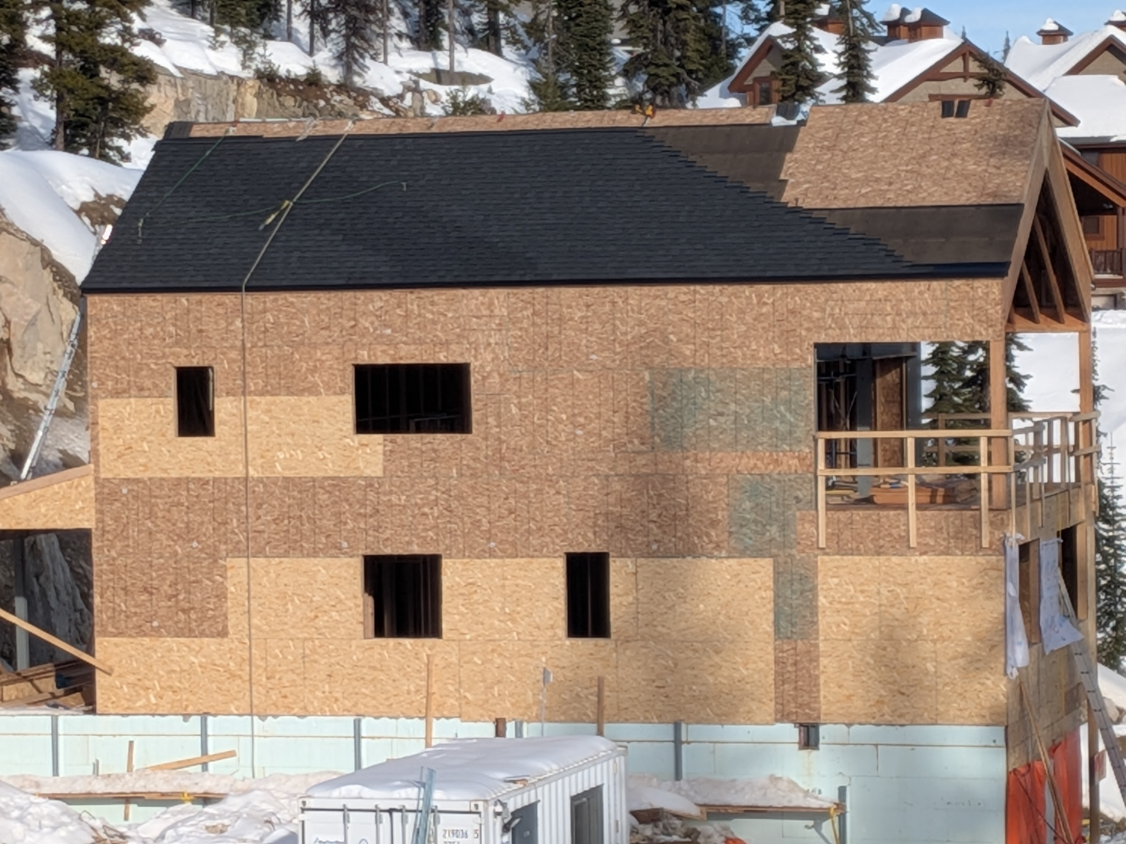 New construction dark shingle roof on chalet building at Big White Ski Resort in winter