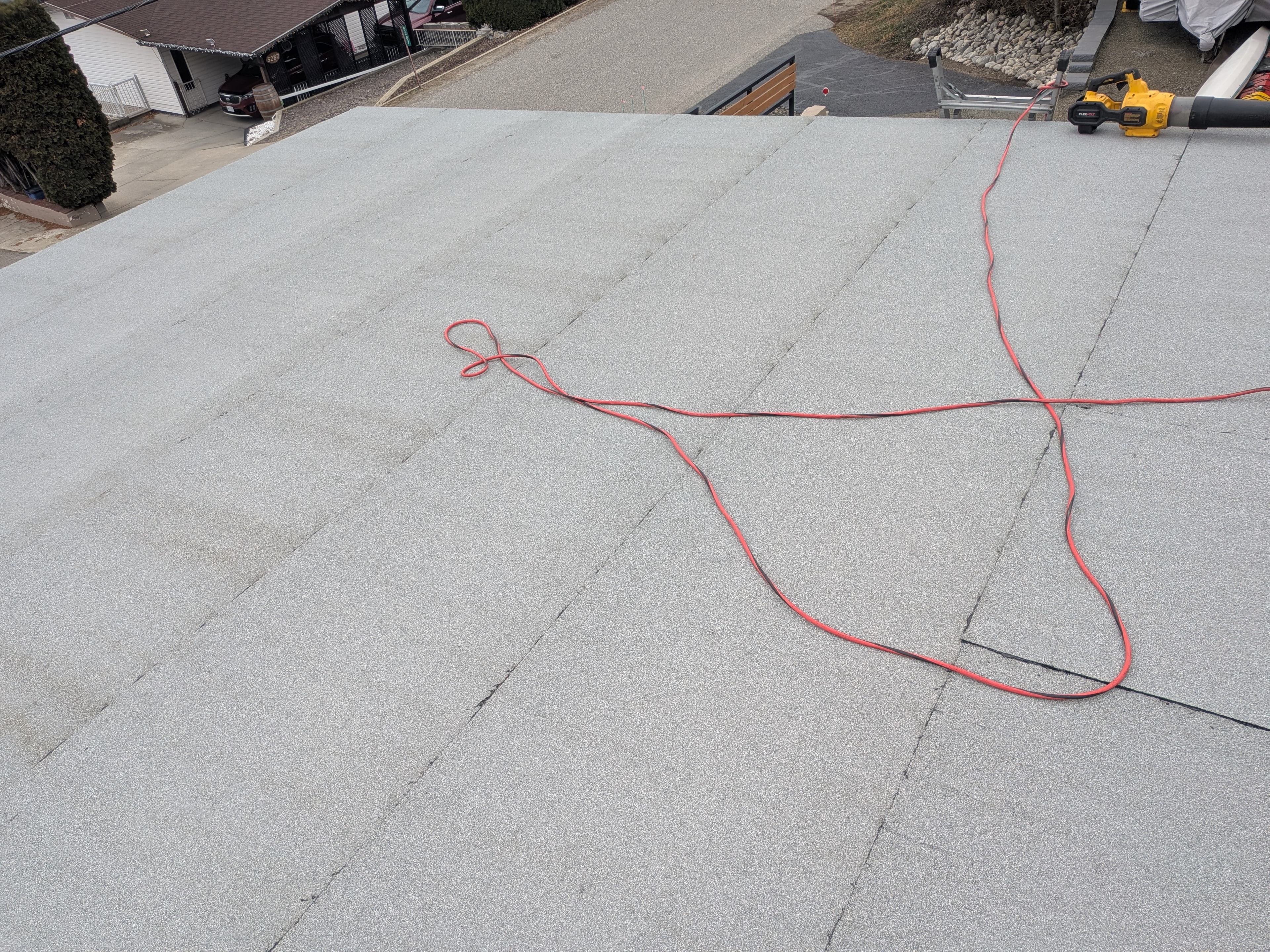 Completed flat torch-on membrane roof with DeWalt blower on residential home