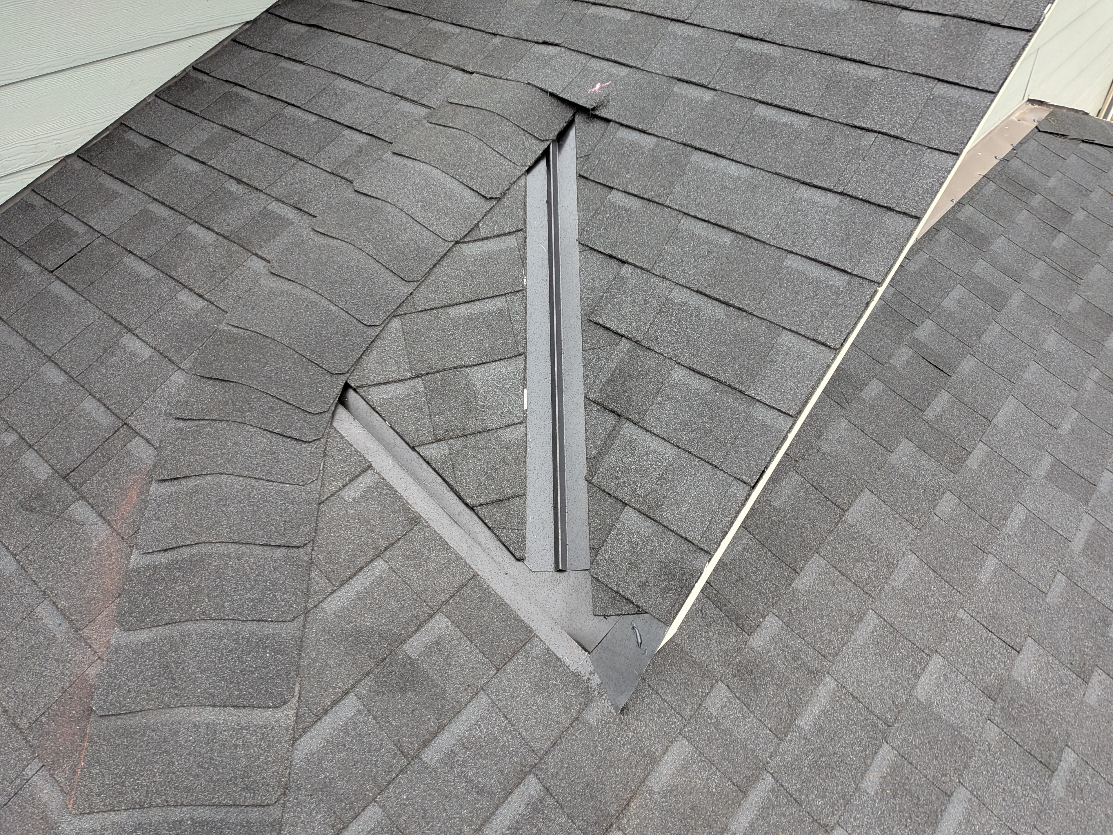 Close-up of valley flashing and step flashing detail on dark grey shingle roof