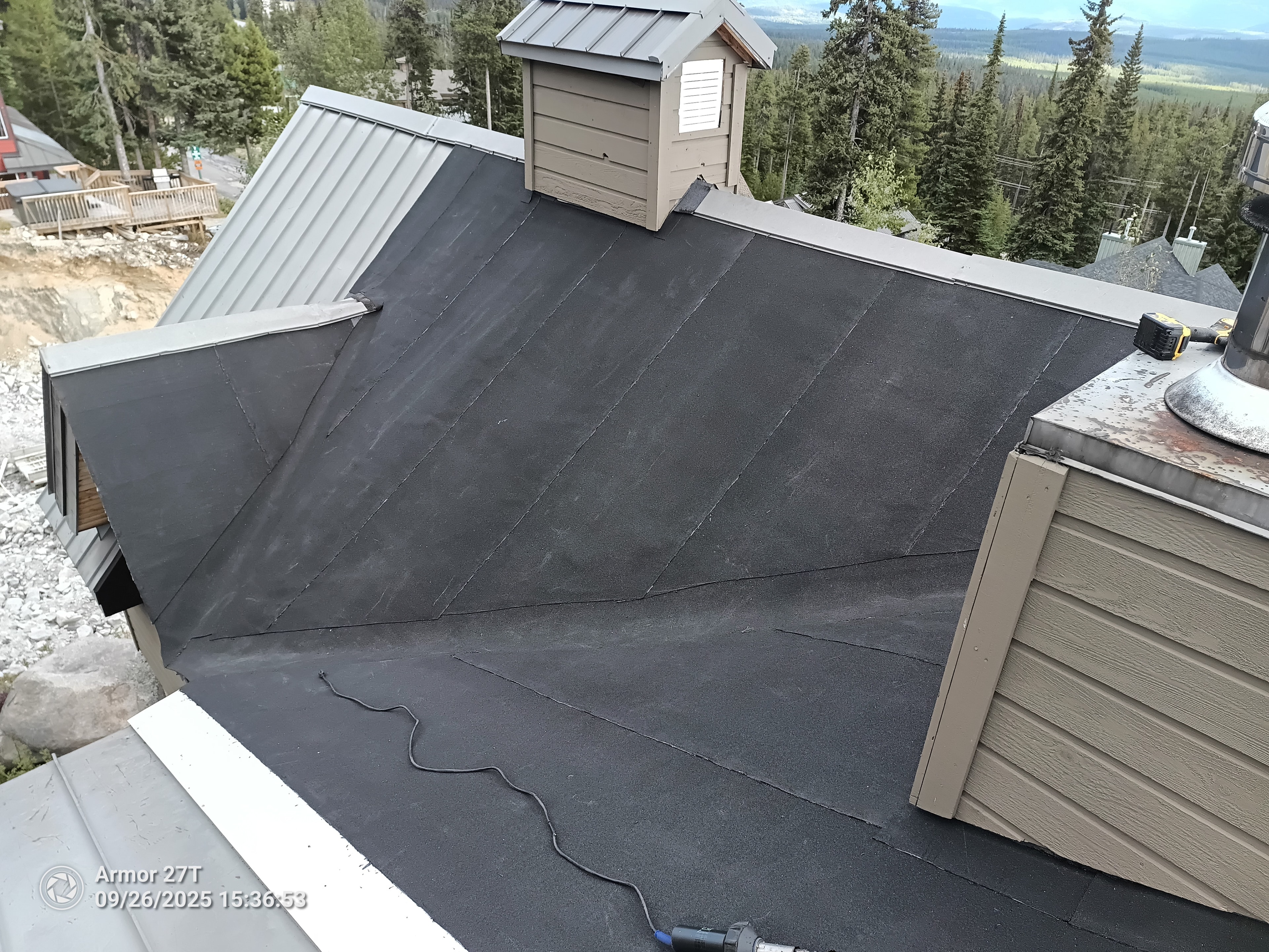 Torch-on flat roof membrane installation on chalet building at Big White with mountain views