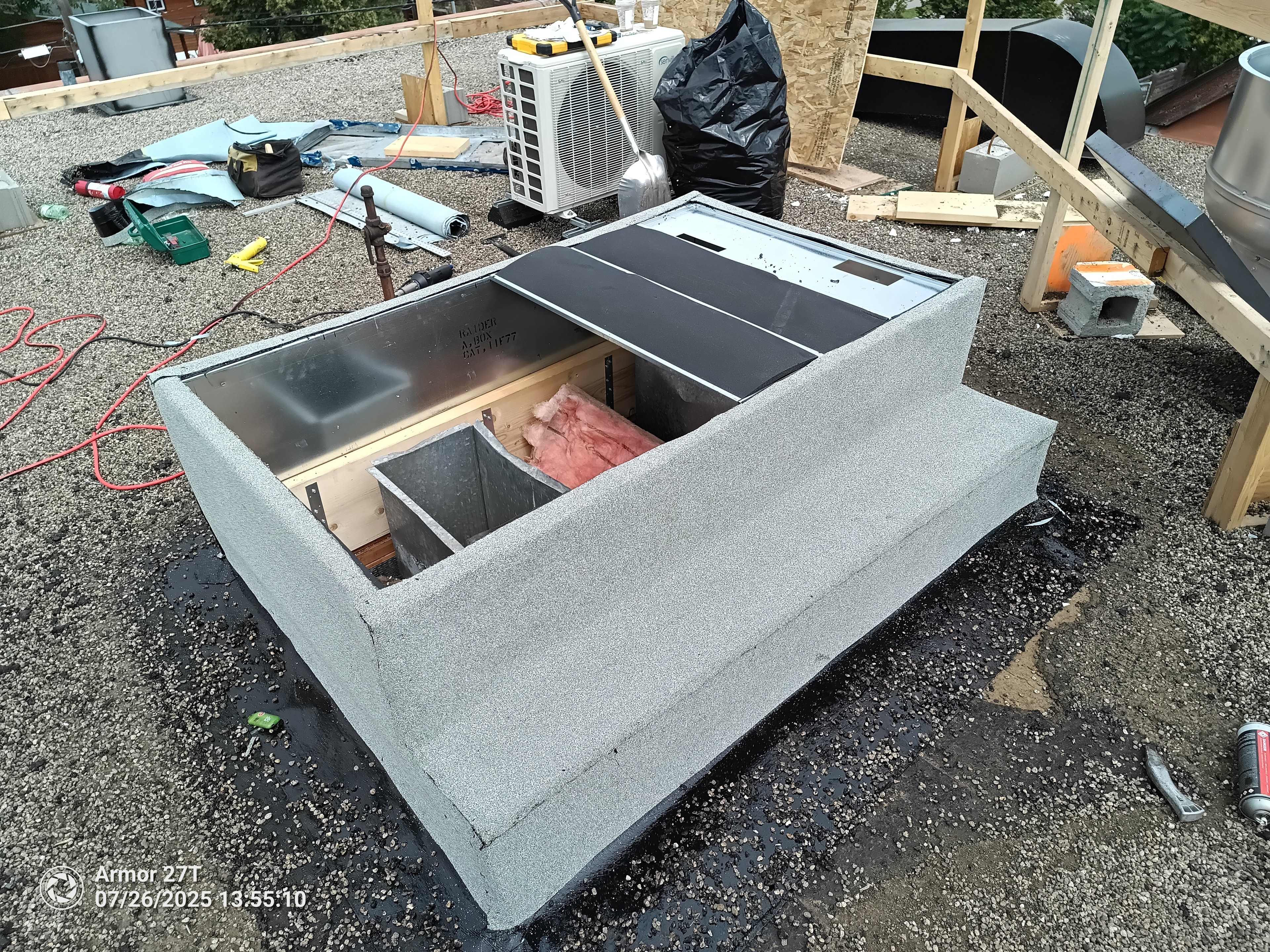 Rooftop skylight curb installation on flat gravel roof with HVAC unit and framing