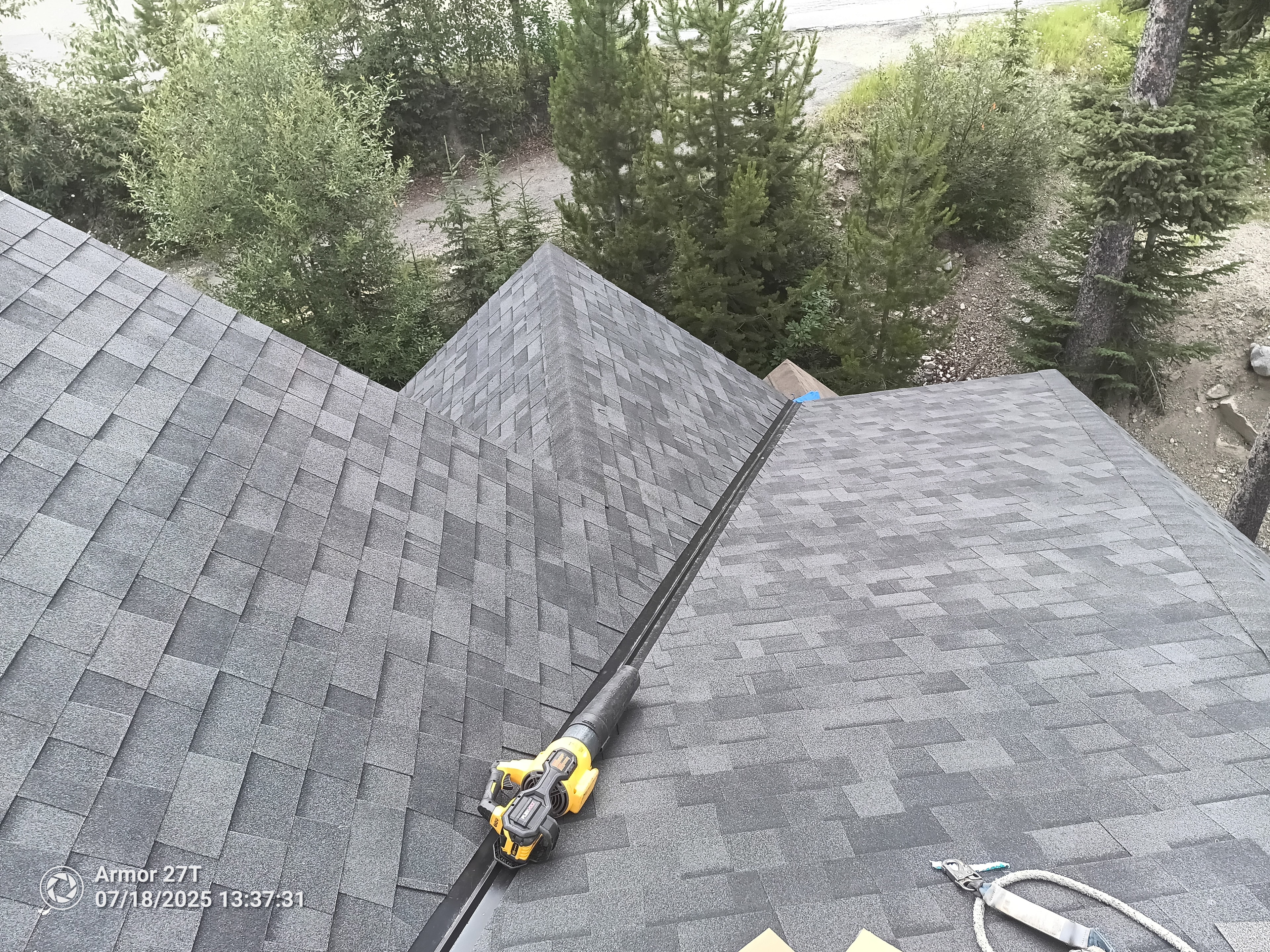 Completed shingle roof with ridge vent and forest views