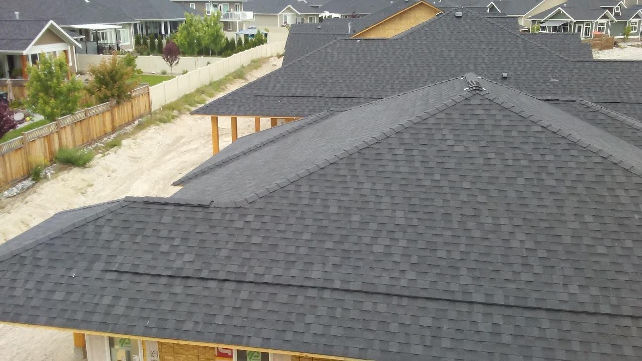 Aerial view of completed dark shingle roofs on new construction homes
